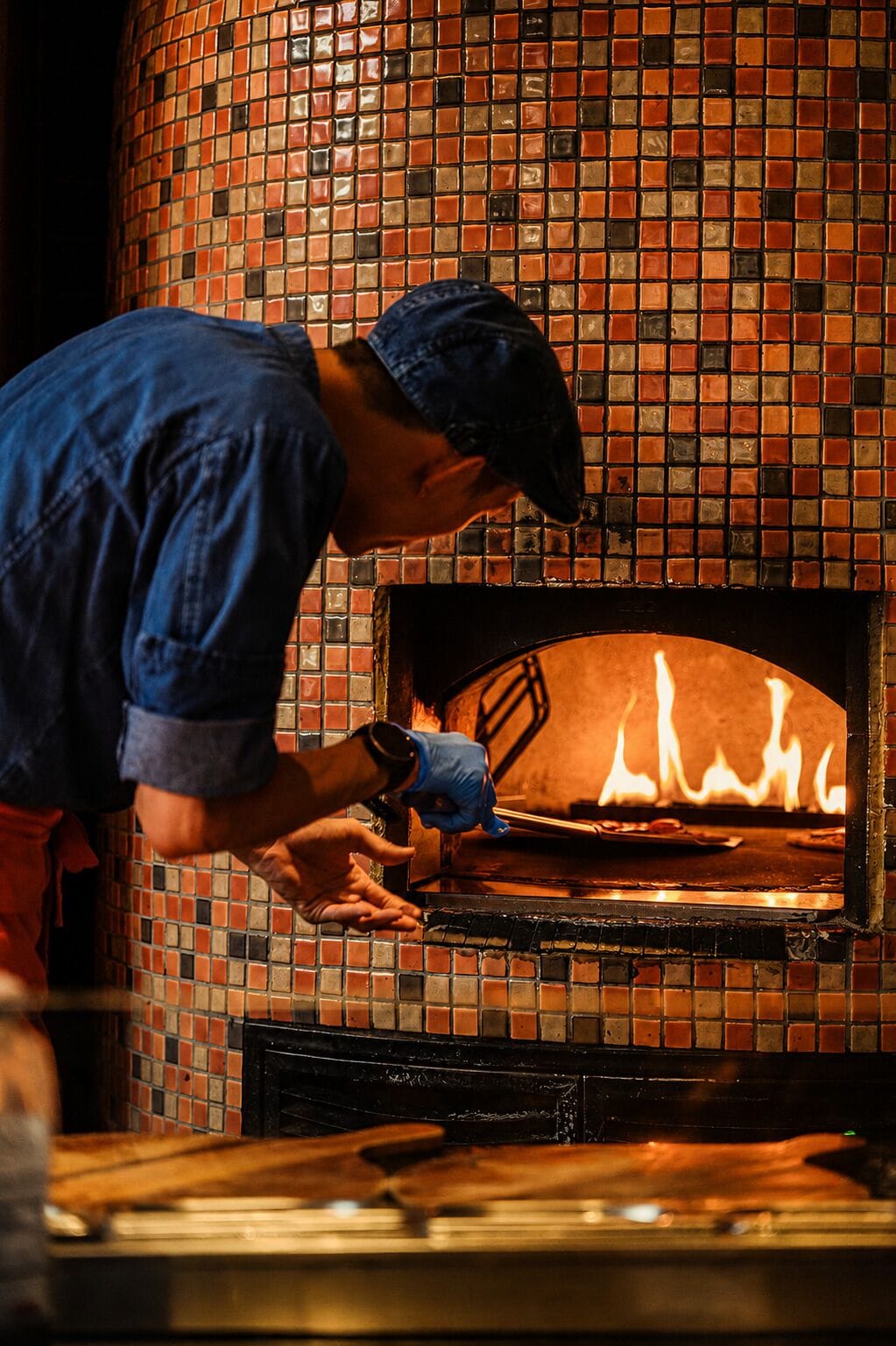 Una persona operando un horno de pizza de ladrillo.
