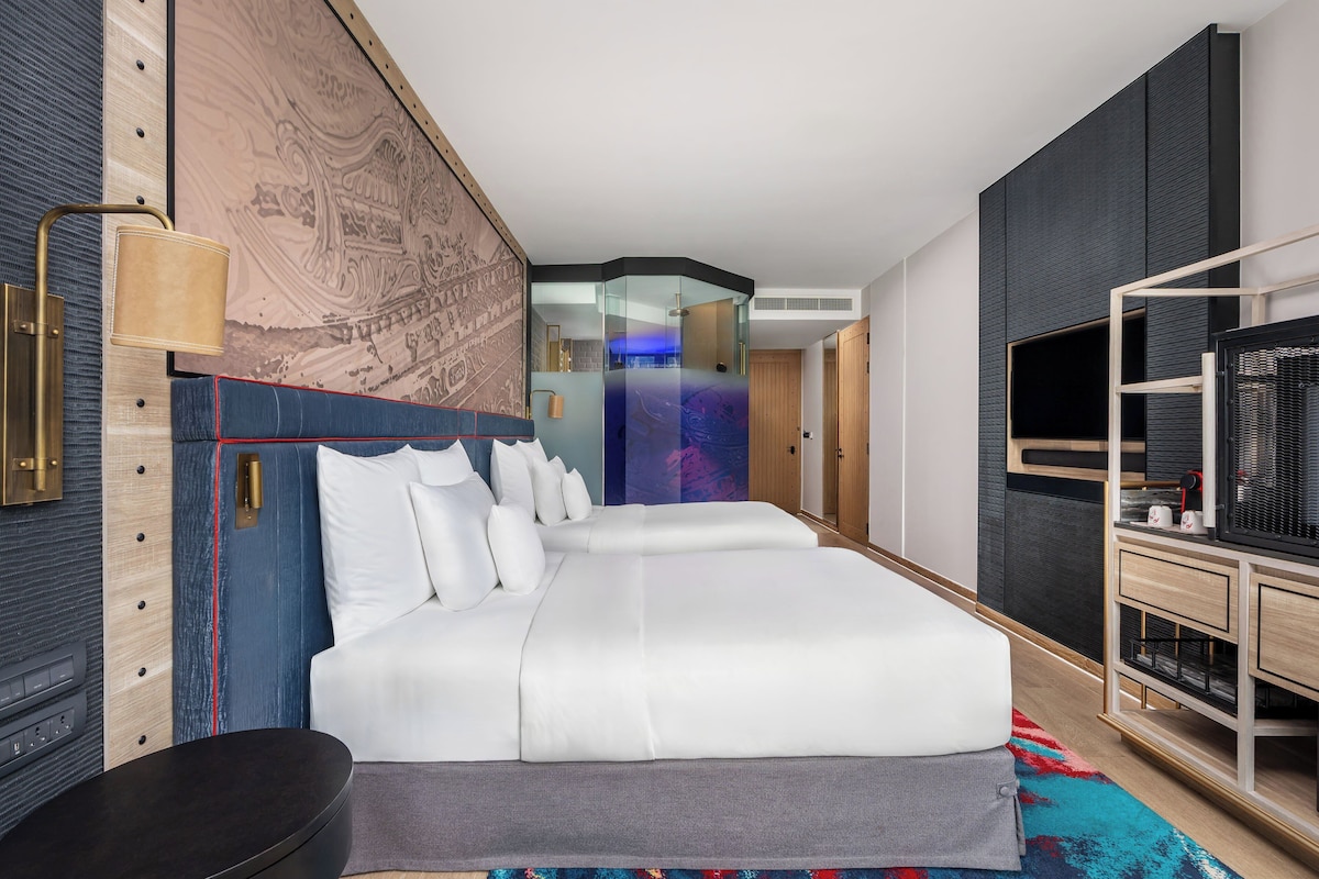 Una habitación de hotel moderna con una cama grande, un escritorio, un televisor y un armario.