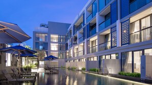 Een modern hotel met een zwembad, ligbedden en parasols.