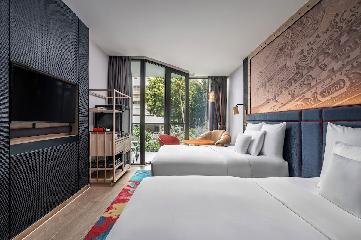 Habitación de hotel moderna con una cama grande, televisión, escritorio y vista a zonas verdes.