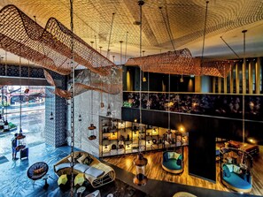 A spacious lobby with a high ceiling, hanging lights, and a view of the street below. - Hotel Indigo Phuket Patong by IHG (Patong)