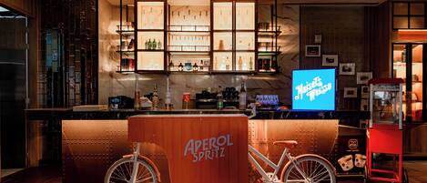 Zona de bar con mostrador de madera, un letrero de neón y una bicicleta.
