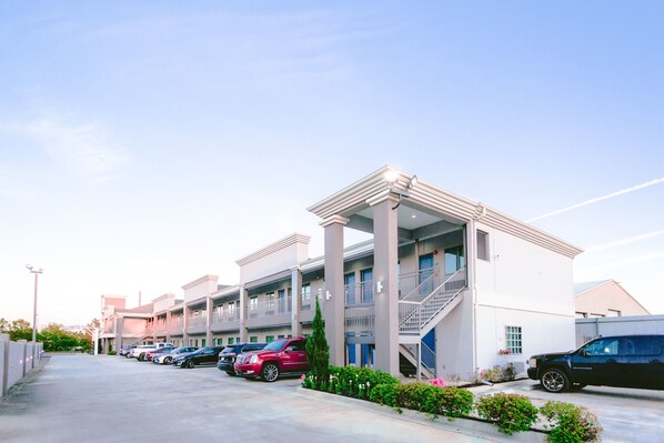 A hotel with a row of parking spaces and a covered walkway. - Express Inn - Spring (Spring)