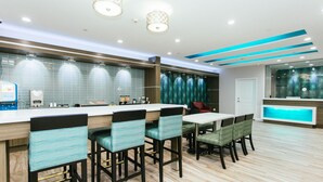 Cocina moderna con barra, piso de madera y una zona de estar con sillas y mesa.