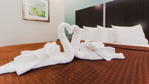 Habitación de hotel con una cama bien hecha, un cuadro enmarcado en la pared y un cabecero oscuro.
