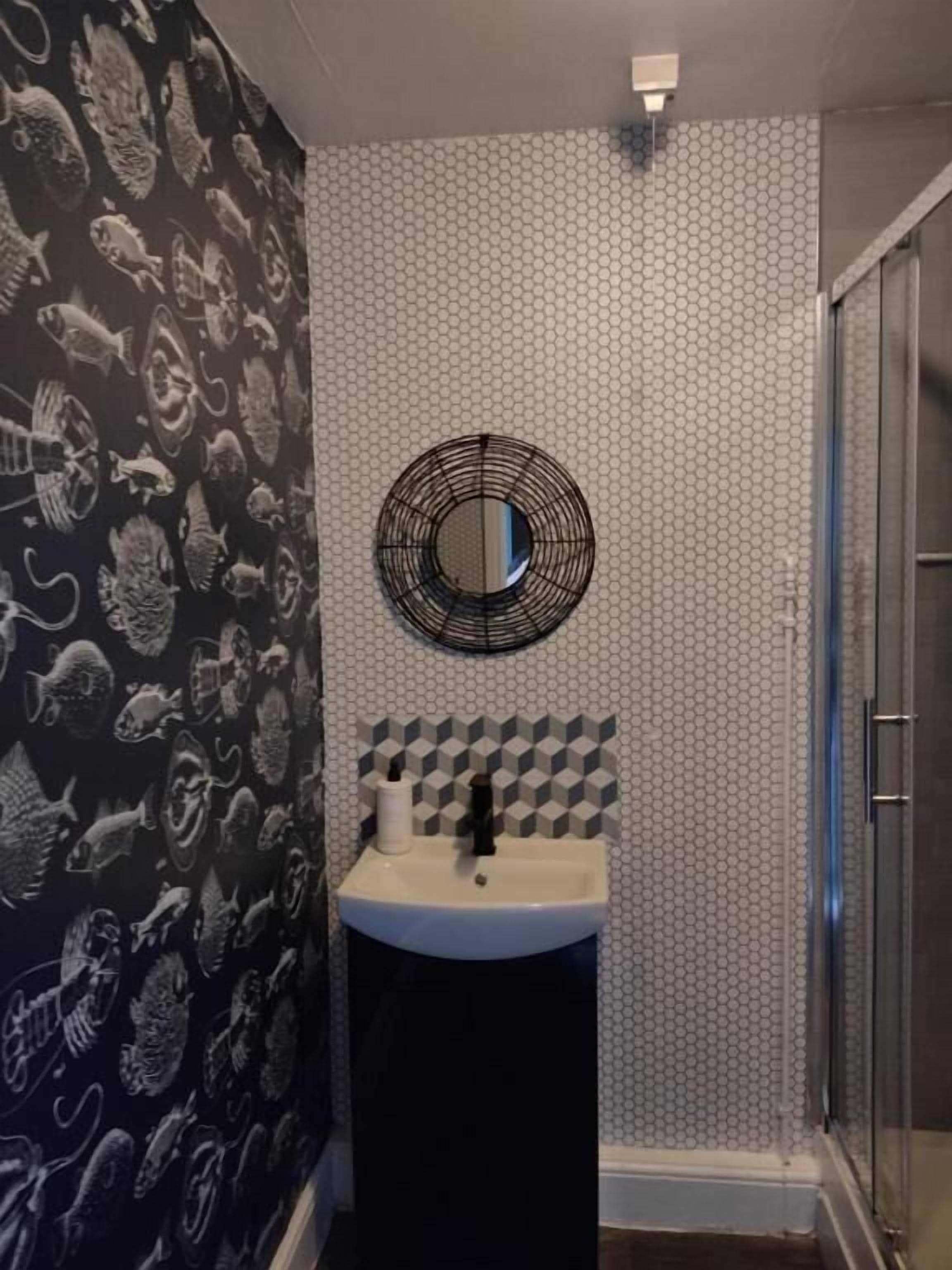 A bathroom with a sink, mirror, and shower.