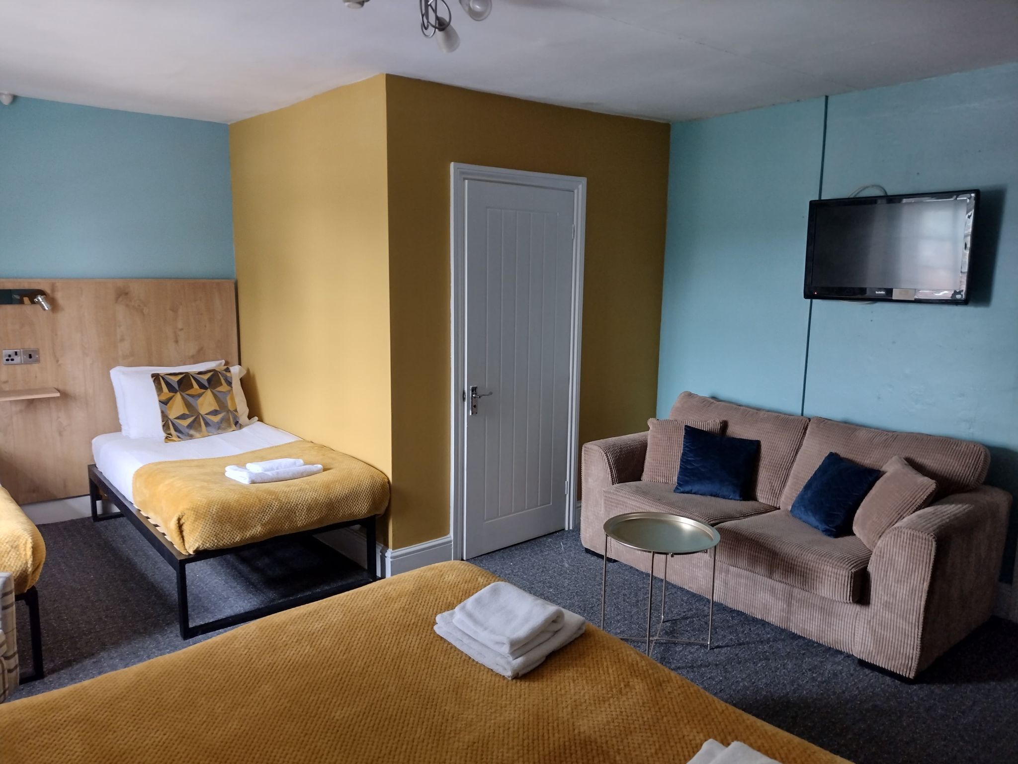 Une chambre d’hôtel avec deux lits, un canapé, une télévision et une petite table.