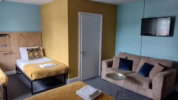 Une chambre d’hôtel avec deux lits, un canapé, une télévision et une petite table.