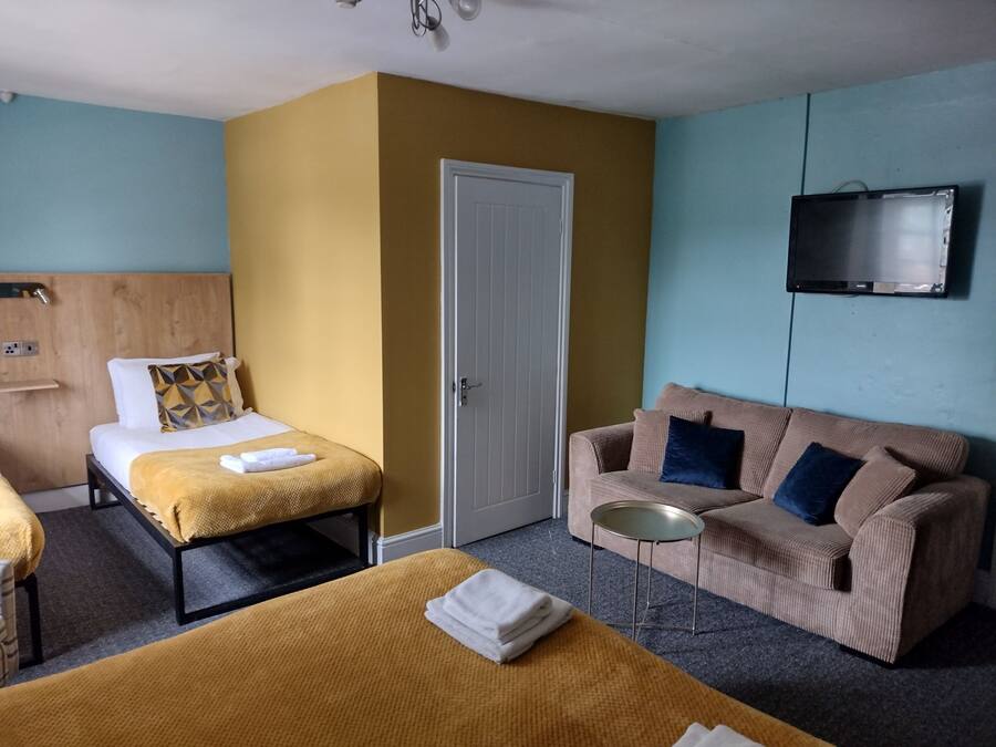 Une chambre d’hôtel avec deux lits, un canapé, une télévision et une petite table.