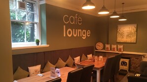 Un salón de café con una mesa de madera, sillas, un reloj y una chimenea.