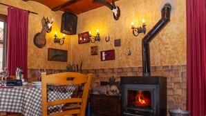 A cozy room with a fireplace, wooden furniture, and wall-mounted decor. - Hostal Hostatgeria Sant Jaume (La Pobla de Benifassa)