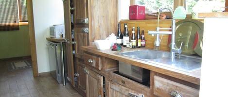 A kitchen with wooden cabinets, a stainless steel sink, and various bottles on the counter.