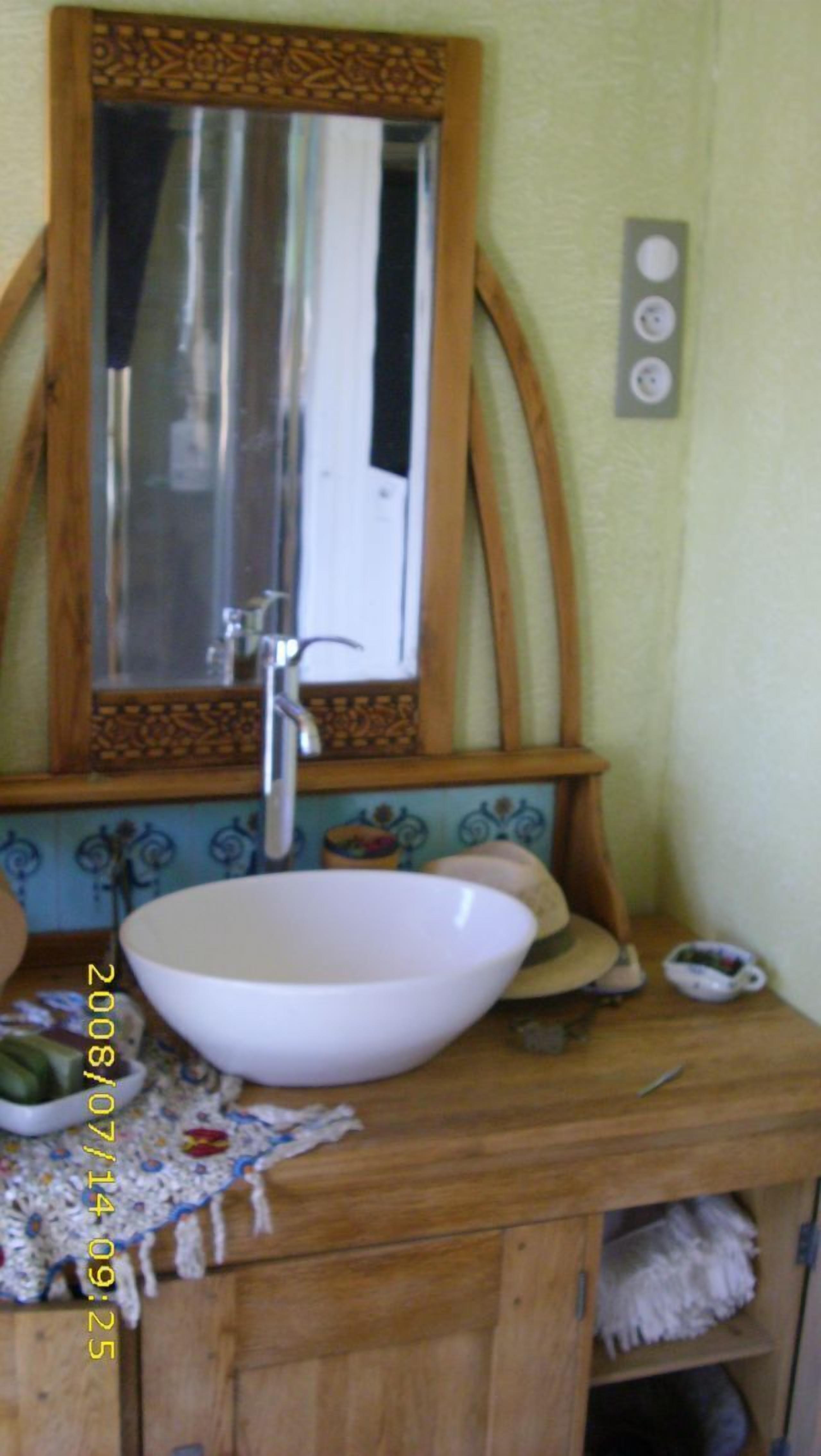 Une salle de bain avec un meuble-lavabo en bois, un lavabo blanc, un miroir et un porte-serviettes.