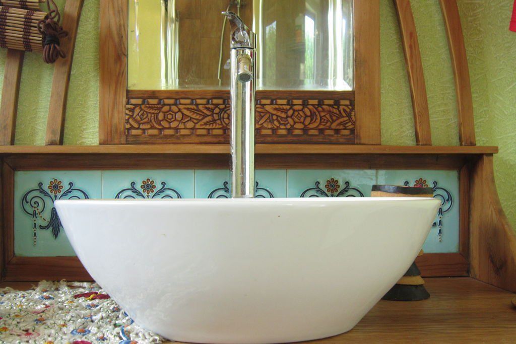 A white ceramic sink with a modern faucet in a bathroom with wooden trim and decorative tiles.