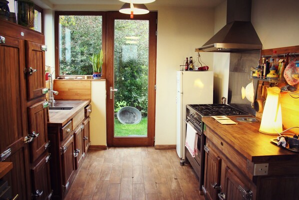 Una cocina con armarios de madera, estufa y vistas a un jardín a través de un ventanal.