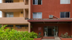 A multi-story building with a red facade, balconies, and a sign indicating a laundry facility.