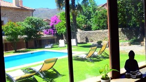 A view of a swimming pool with lounge chairs and a Buddha statue. - Hotel Rural Duende del Chafaril (San Martin de Trevejo)