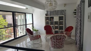 Een moderne woonkamer met een groot raam, een witte boekenkast en rieten stoelen.