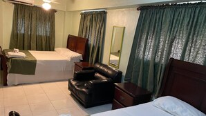 Een hotelkamer met twee bedden, een leren fauteuil, een nachtkastje, een spiegel en een airconditioning.