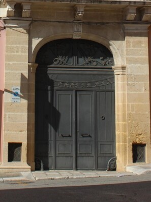 A double door with a decorative arch above it, set in a stone building.