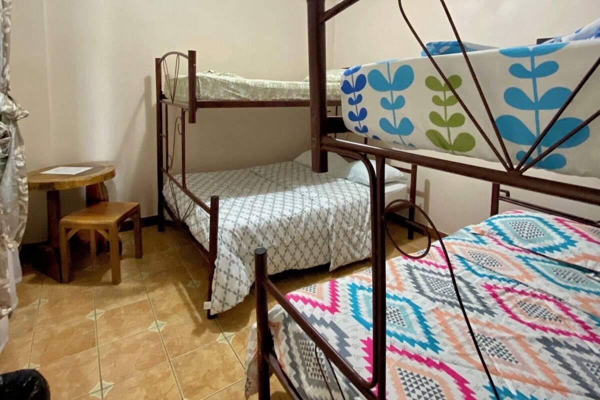 Un dormitorio con literas, una pequeña mesa de madera y una silla.