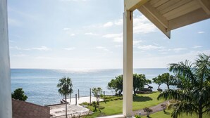 A view from a balcony overlooking a beach with palm trees and a clear sky. - Beach Studio  at Point Village Resort (Negril)