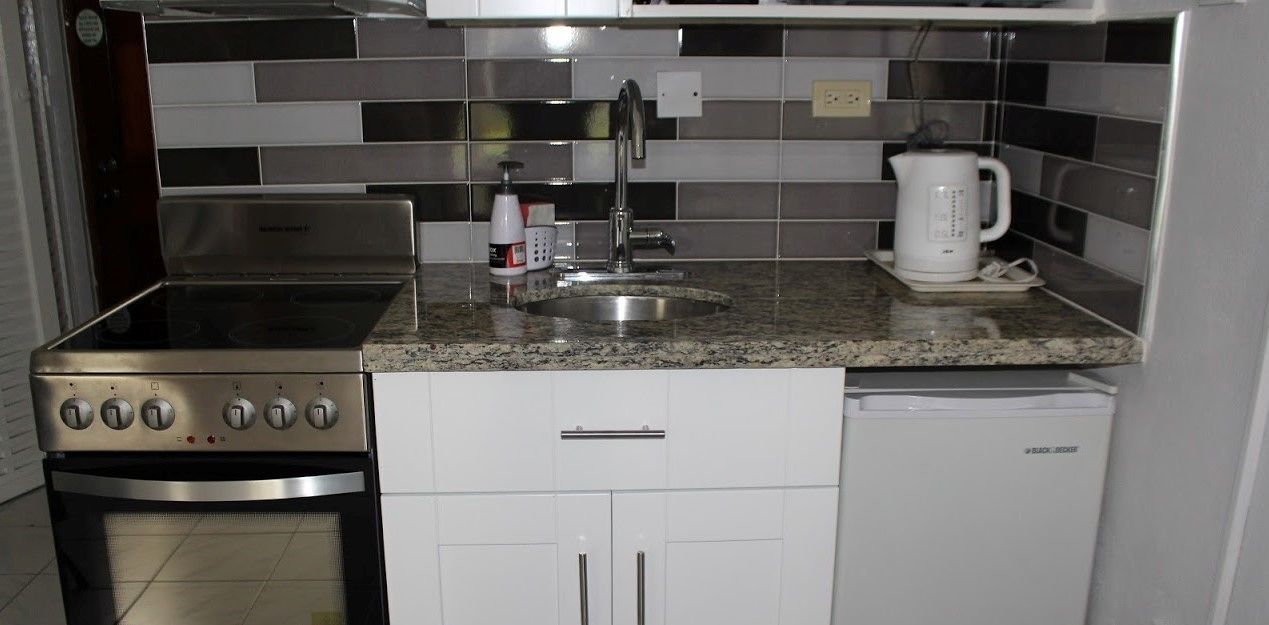 A compact kitchen with a stainless steel stove, a sink, and a coffee maker.