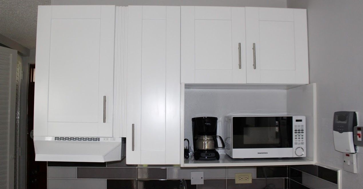 A kitchen with white cabinets, a microwave, and a coffee maker.