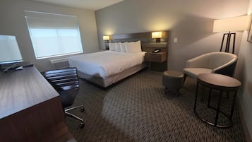Ein Hotelzimmer mit einem Bett, Nachttischen, einem Schreibtisch, einem Stuhl und einer Lampe.