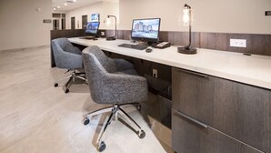 A reception desk with two computer monitors, a telephone, and a lamp. There are two office chairs and a trash bin. - Wingate by Wyndham Austin North (Austin)