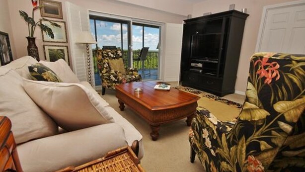 Ein Wohnzimmer mit Sofa, Sessel, Couchtisch und Fernseher.