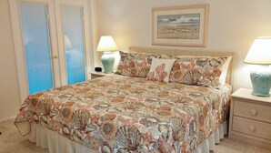 Un dormitorio con cama, dos lámparas de noche, una mesita de noche, un aparador y un cuadro enmarcado en la pared.