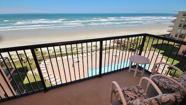 Ein Balkon mit Blick auf Strand und Meer. Dort stehen Liegestühle und es gibt einen kleinen Pool.