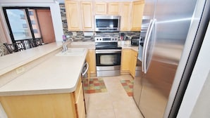 Eine moderne Küche mit Holzausstattung, Edelstahlgeräten und einer großen Kücheninsel mit Spüle.
