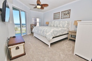 A bedroom with a bed, a ceiling fan, a desk, a chair, and a wardrobe.