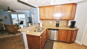 A kitchen with wooden cabinets, a stainless steel dishwasher, and a granite countertop. - Oceanwalk 18-406 Apartment 2 (New Smyrna Beach)
