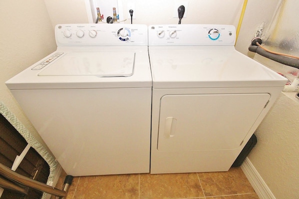 A front-loading washer and dryer in a laundry room with a tiled floor.