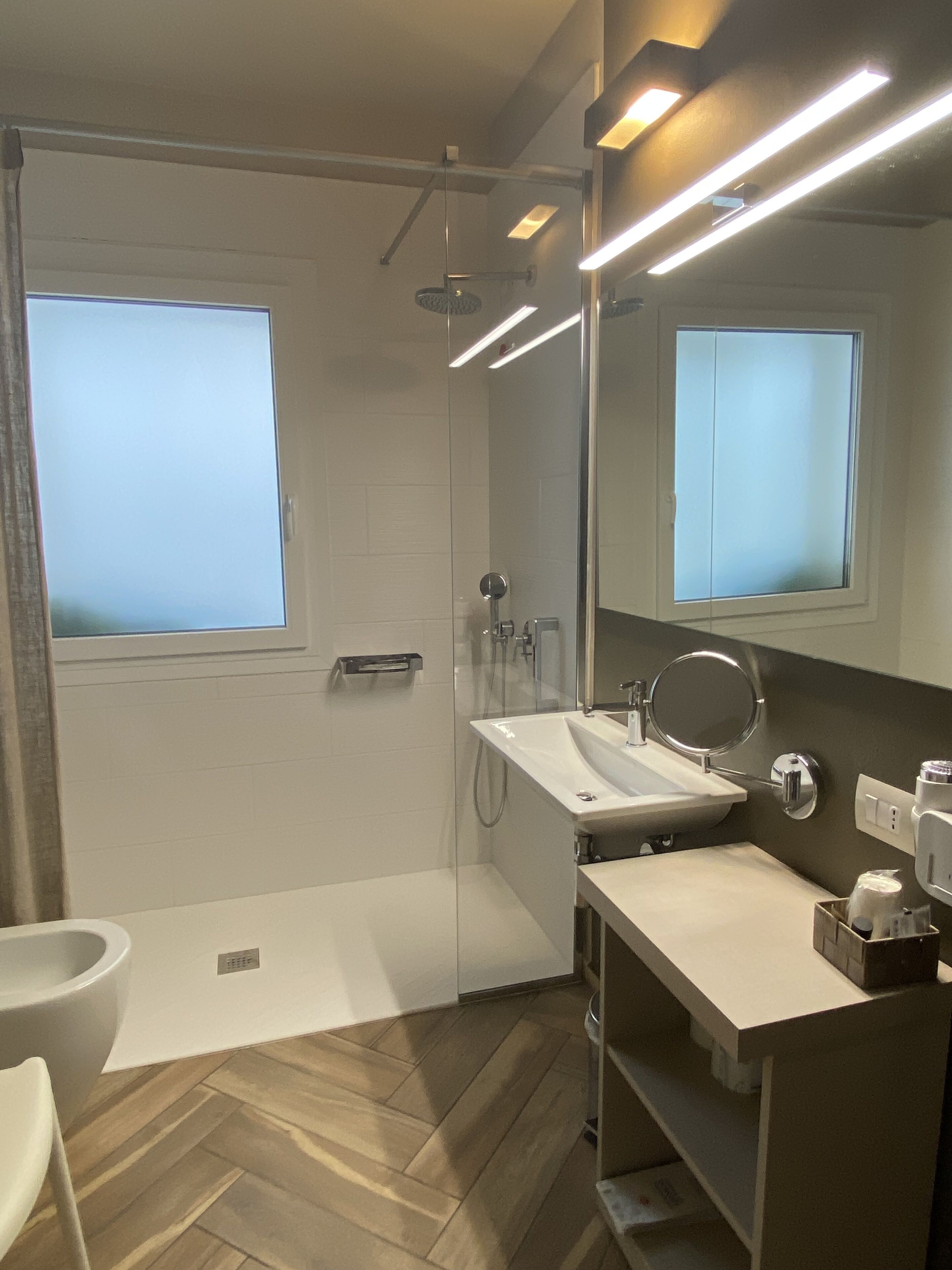 A modern bathroom with a shower, sink, and mirror.