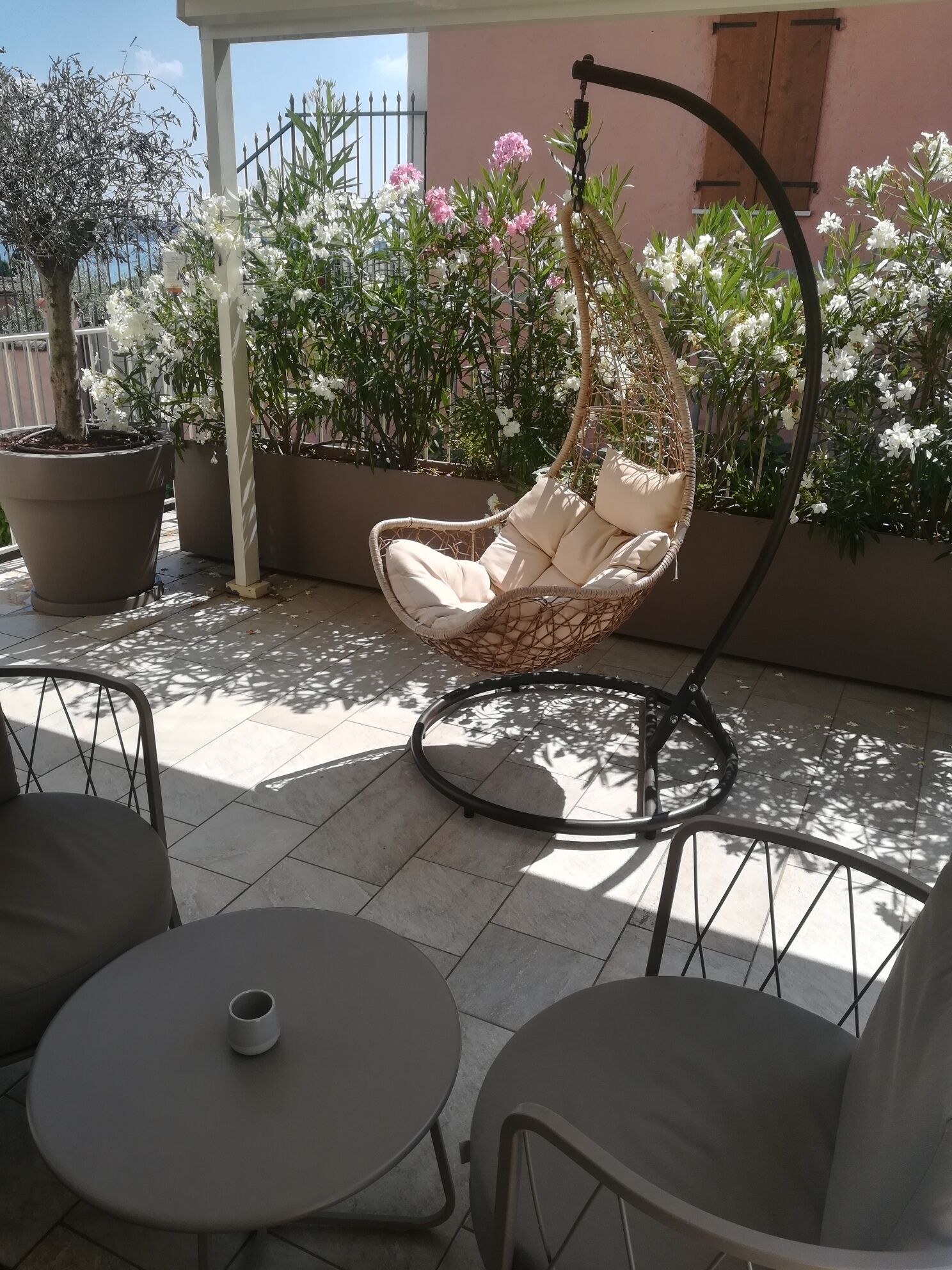 A patio with a hanging chair, a round table, and potted plants.