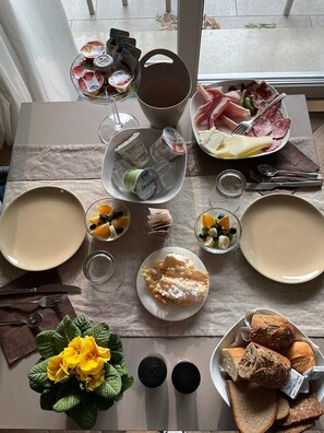 A breakfast setting with plates of food, including pastries, bread, and a fruit bowl. - L.A. Home (Moniga del Garda)