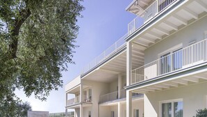 A modern multi-story residential building with balconies, large windows, and a well-maintained lawn. - L.A. Home (Moniga del Garda)