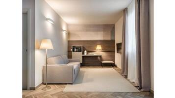 Un couloir d’hôtel moderne, avec un canapé, une lampe et une petite table.