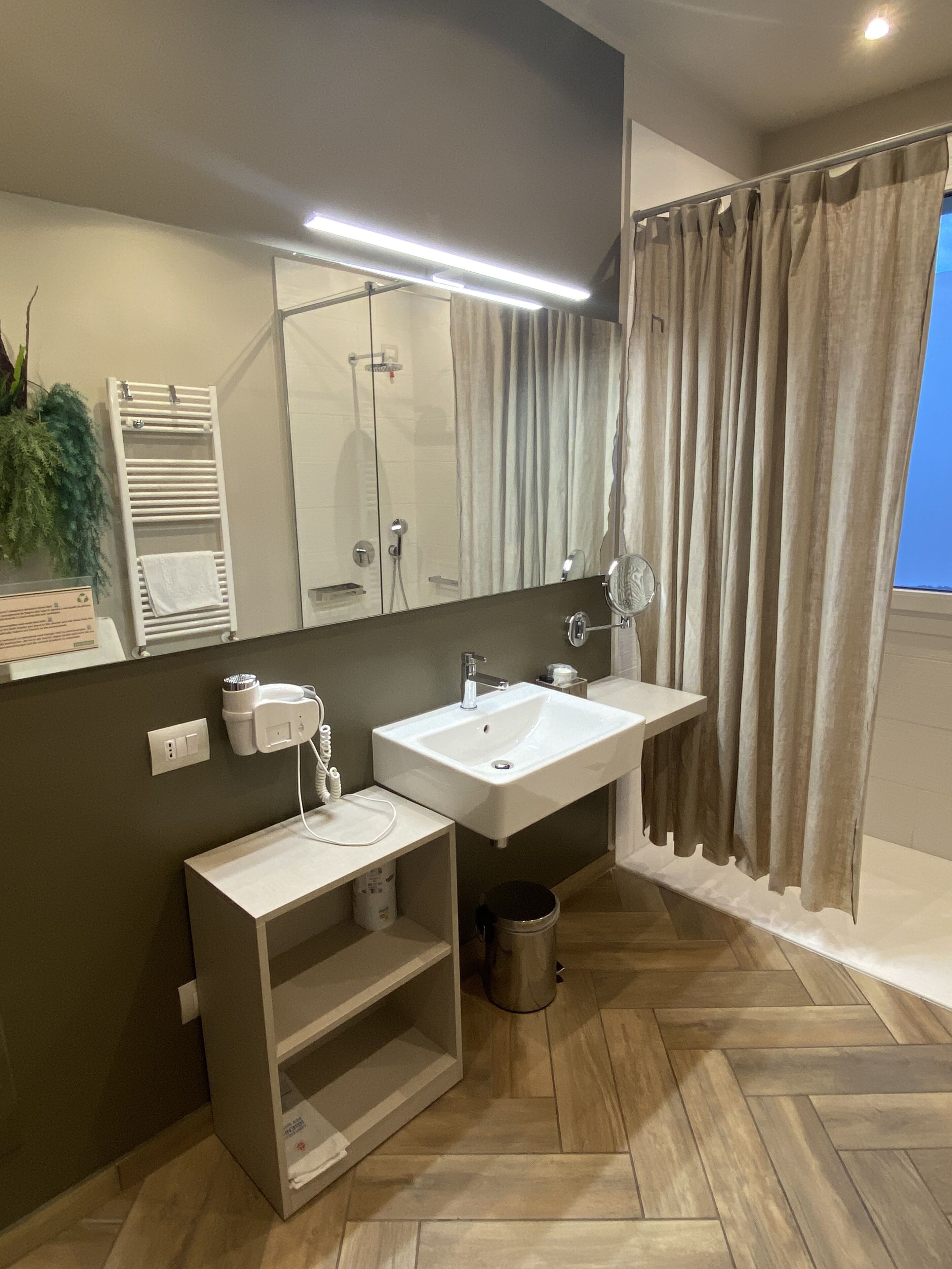 Une salle de bain moderne avec un grand miroir, deux lavabos, un porte-serviettes et une douche.