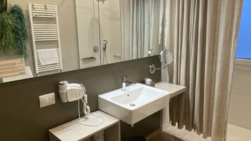Une salle de bain moderne avec un grand miroir, deux lavabos, un porte-serviettes et une douche.