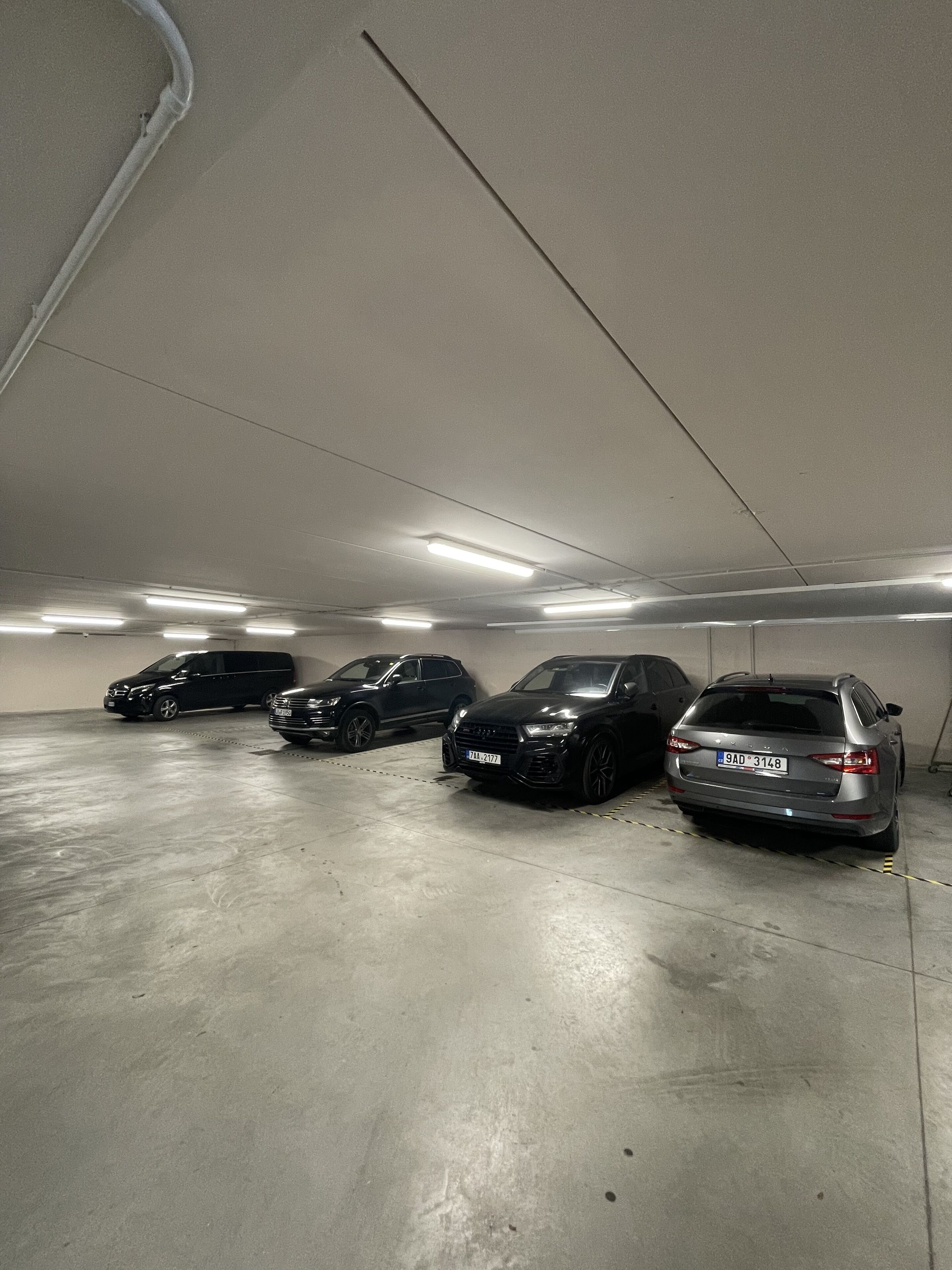 A parking garage with four cars parked in a row.