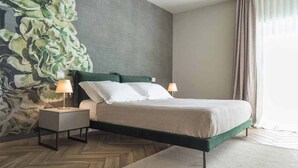 A bedroom with a bed, two bedside tables, a wall mural, and a large window with curtains. - L.A. Home (Moniga del Garda)