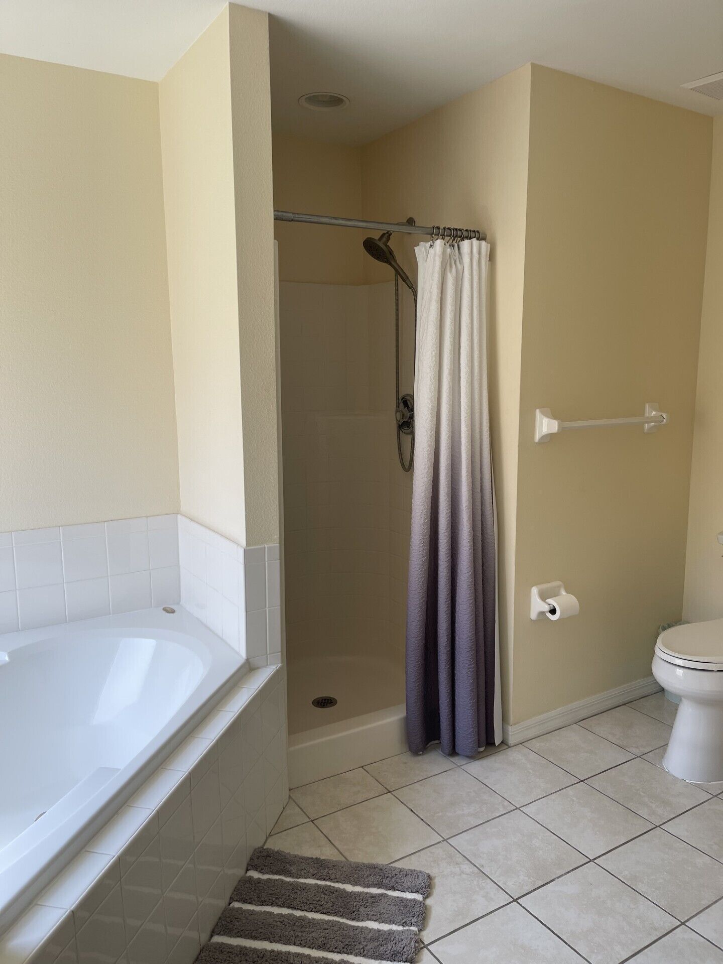 A bathroom with a bathtub, shower, toilet, and a towel rack.