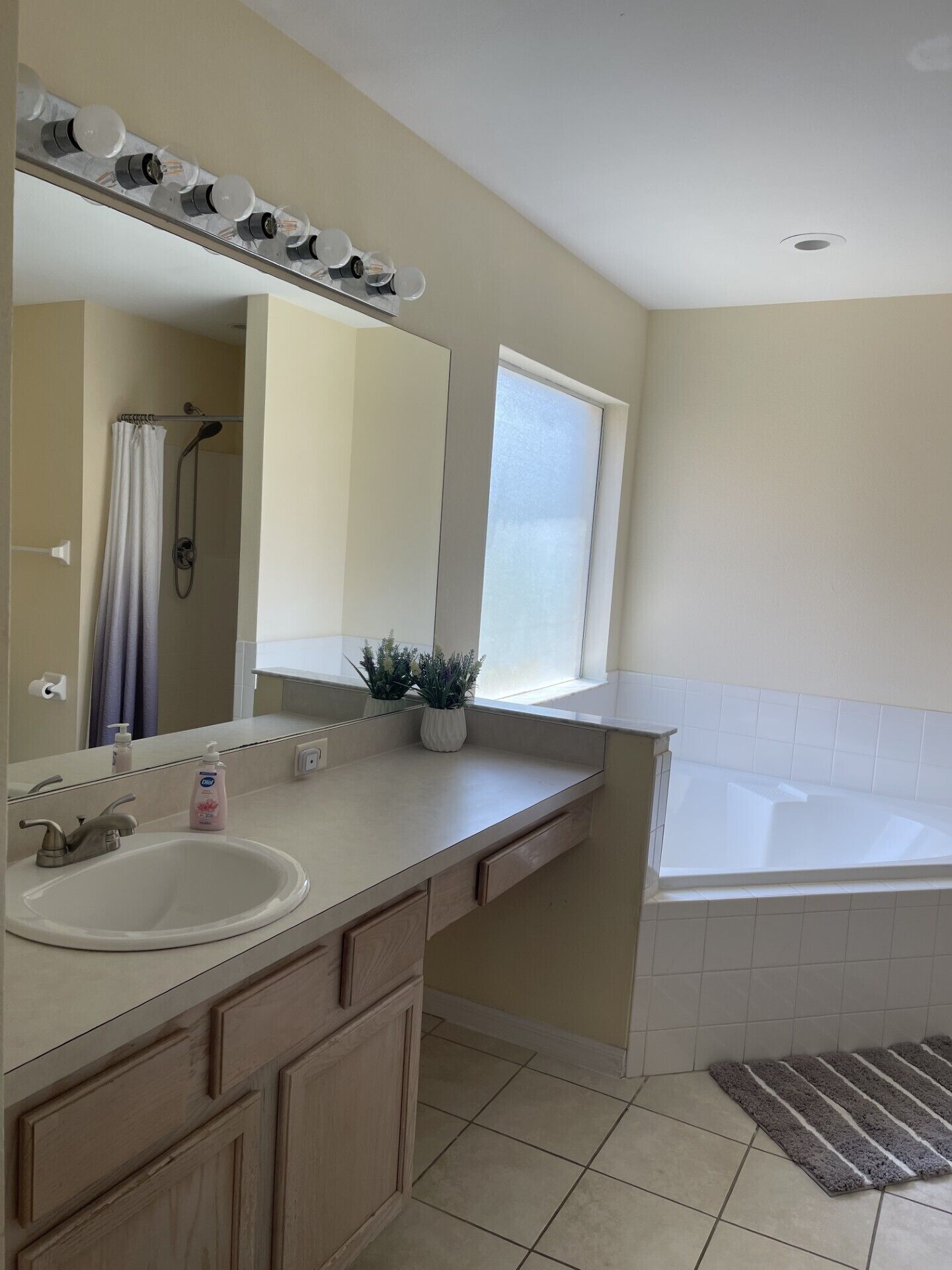 A bathroom with a white sink, mirror, vanity, and a bathtub.