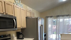 Una cocina moderna con electrodomésticos de acero inoxidable, armarios de madera y suelo de baldosas.