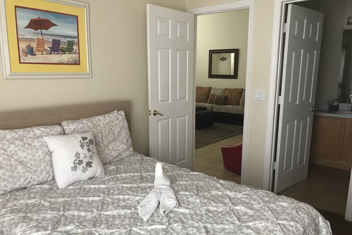Un dormitorio con una cama, una puerta que da a otra habitación y un cuadro en la pared.